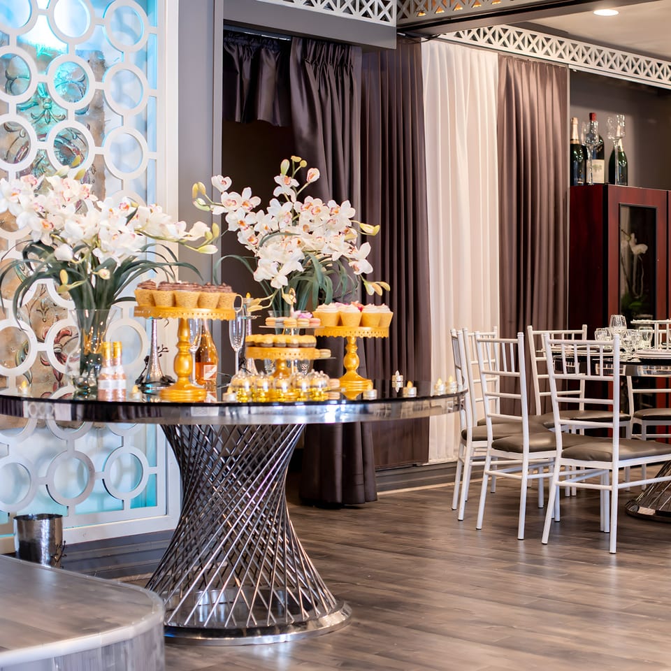 Elegant Fresco Ristorante interior with a dessert table, white orchids, and dining chairs.