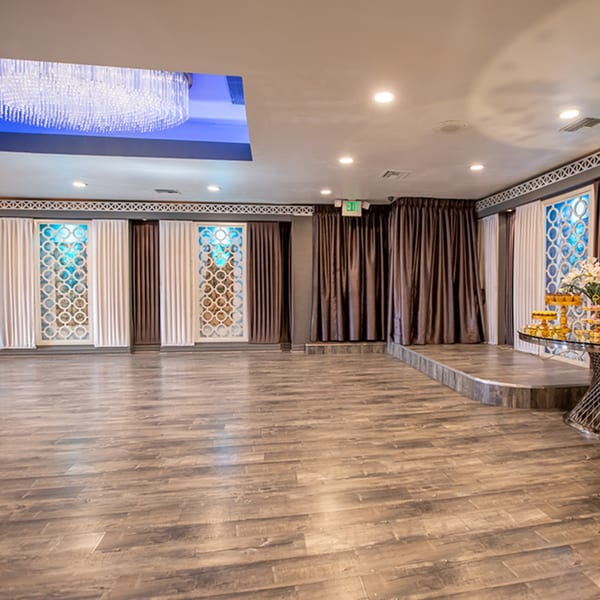 Empty Fresco Ristorante event room with a stage, ornate wall panels, and a large chandelier.