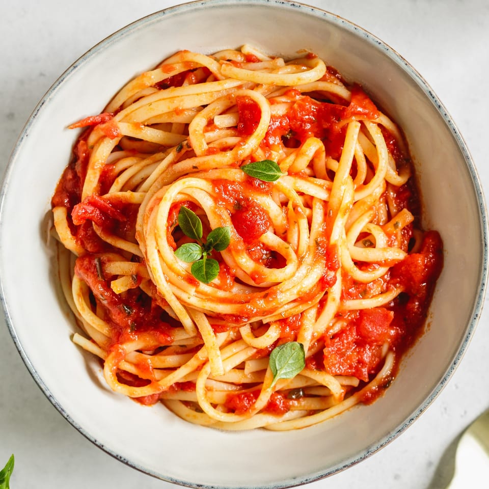 Close-up of Fresco Ristorante's bucatini pasta with chunky red tomato sauce and fresh basil.