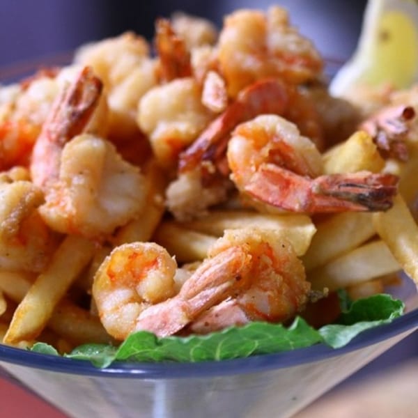 Crispy fried shrimp and golden french fries served in a glass bowl with a lemon wedge.